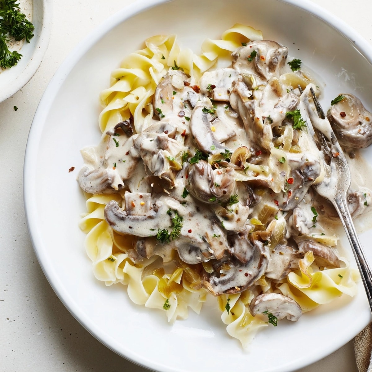 Creamy Mushroom Stroganoff: Sautéed mushrooms simmered in rich sour cream sauce, served over curly egg noodles.