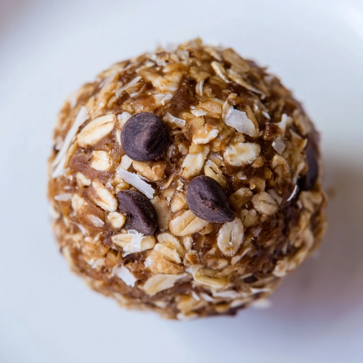 Freshly rolled Chocolate Peanut Butter Energy Balls with oats, chia seeds, and mini dark chocolate chips are displayed on a marble surface.