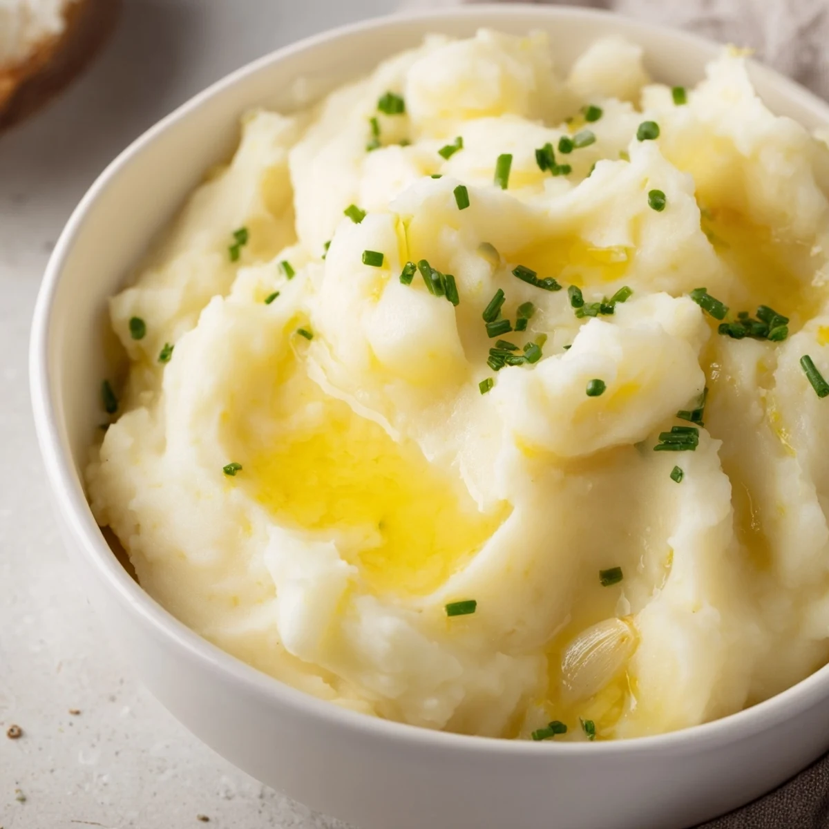 Roasted Garlic Mashed Potatoes topped with fresh chives in a rustic serving bowl, ready to accompany a hearty dinner.