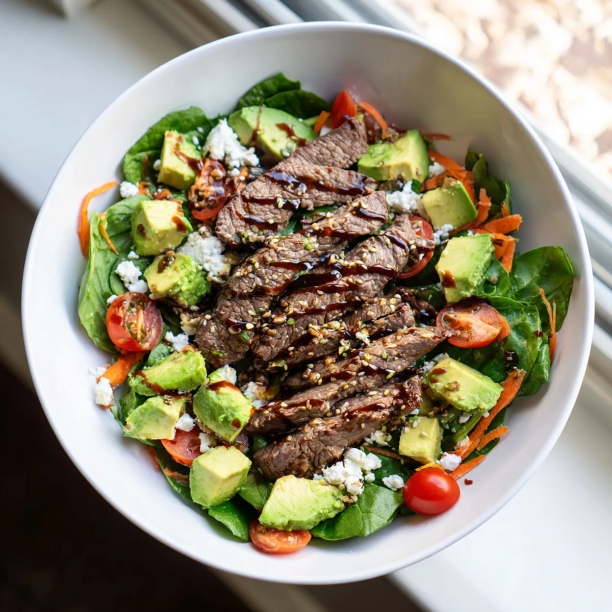 Sliced seared beef, crunchy veggies, and feta garnish make a hearty Beef Salad Bowl serving.