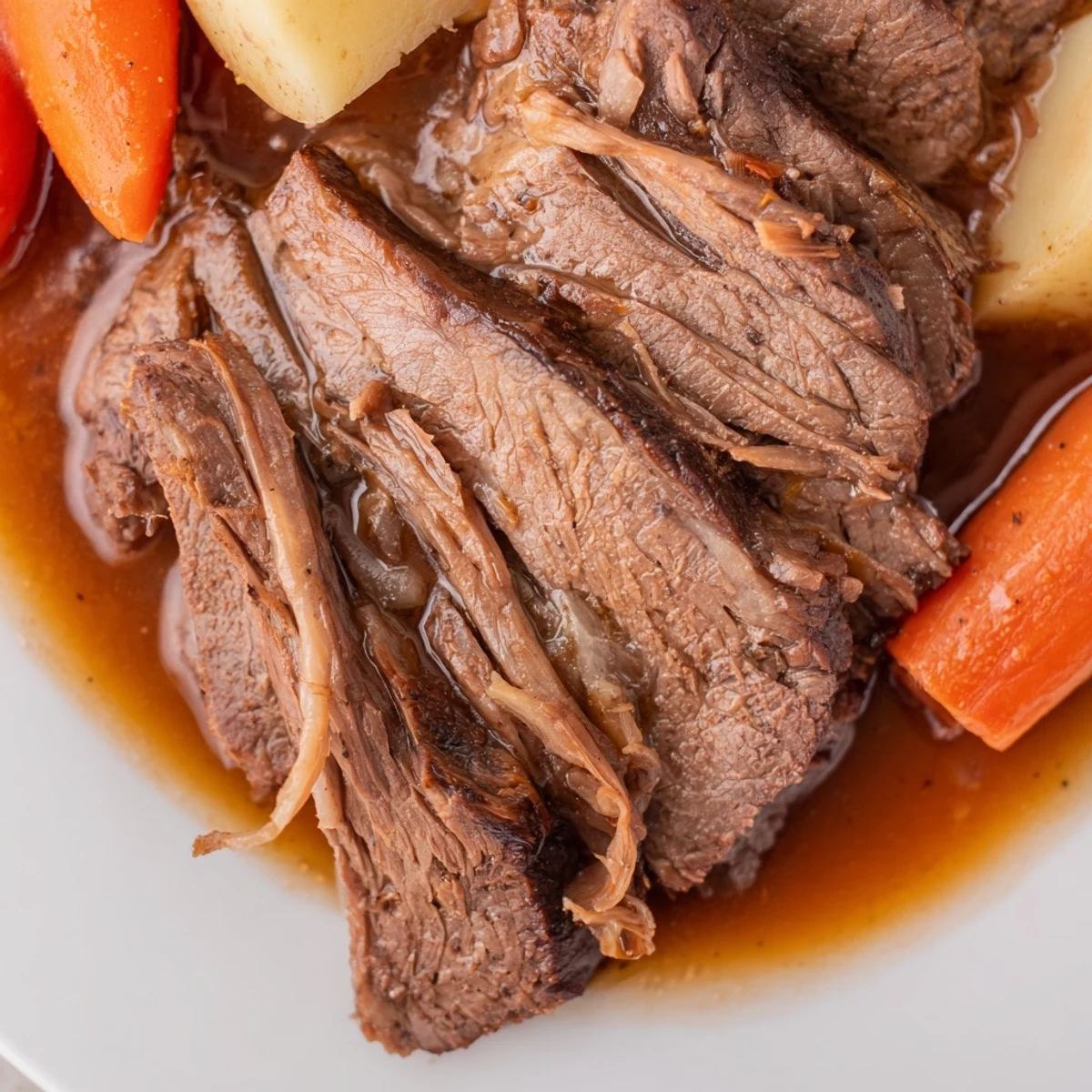 Tender Slow Cooker Beef Roast served with chunky carrots and potatoes on a plate.