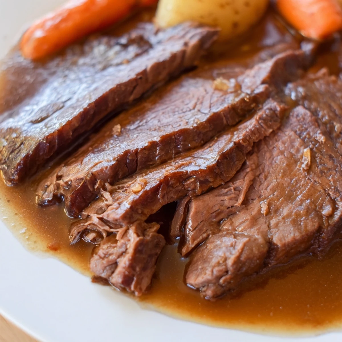 Shredded Slow Cooker Beef Roast in rich gravy with roasted vegetables and fresh herbs.