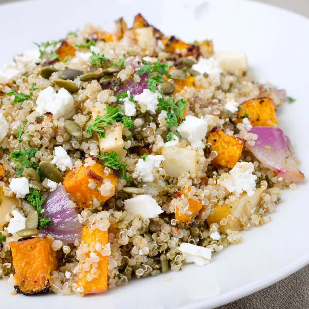Warm Quinoa Salad with Roasted Root Vegetables and Feta served in a rustic bowl, garnished with fresh parsley and golden sweet potatoes.