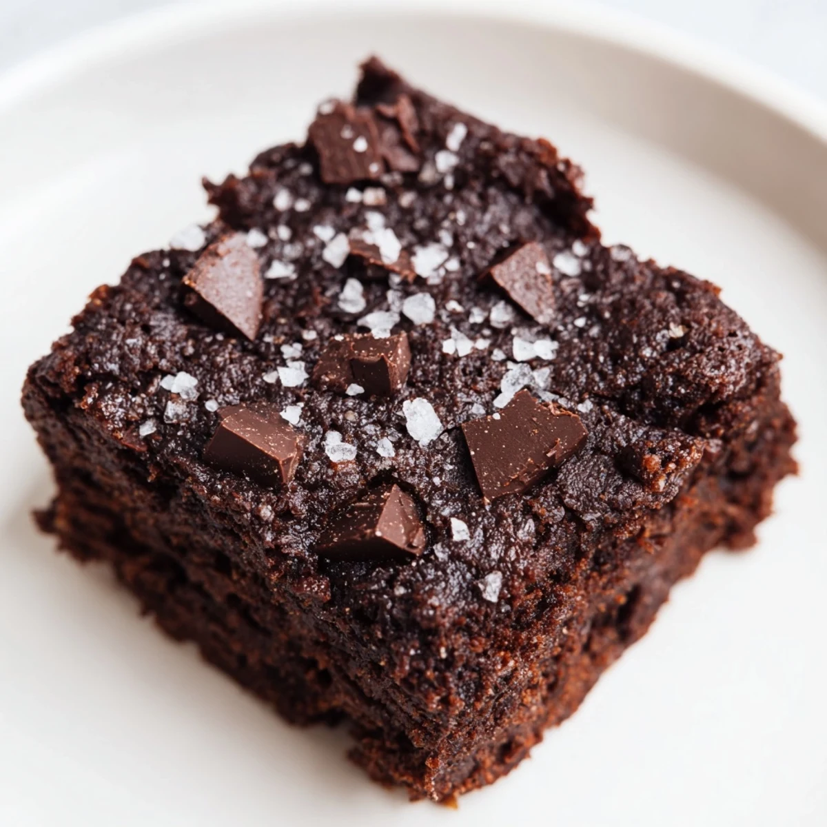 A square of Gluten-Free Almond Flour Brownies with Sea Salt on a plate, ready for a scoop of vanilla ice cream.