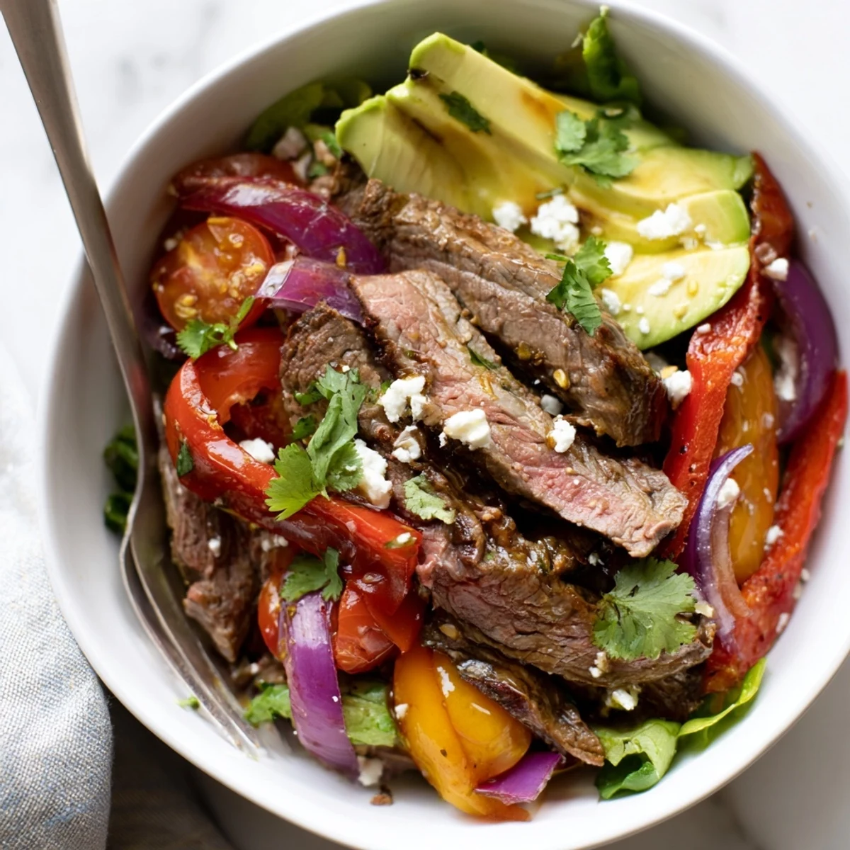 Beef Fajita Salad with Lime Vinaigrette Dressing features grilled steak strips over fresh greens with vibrant sautéed peppers.