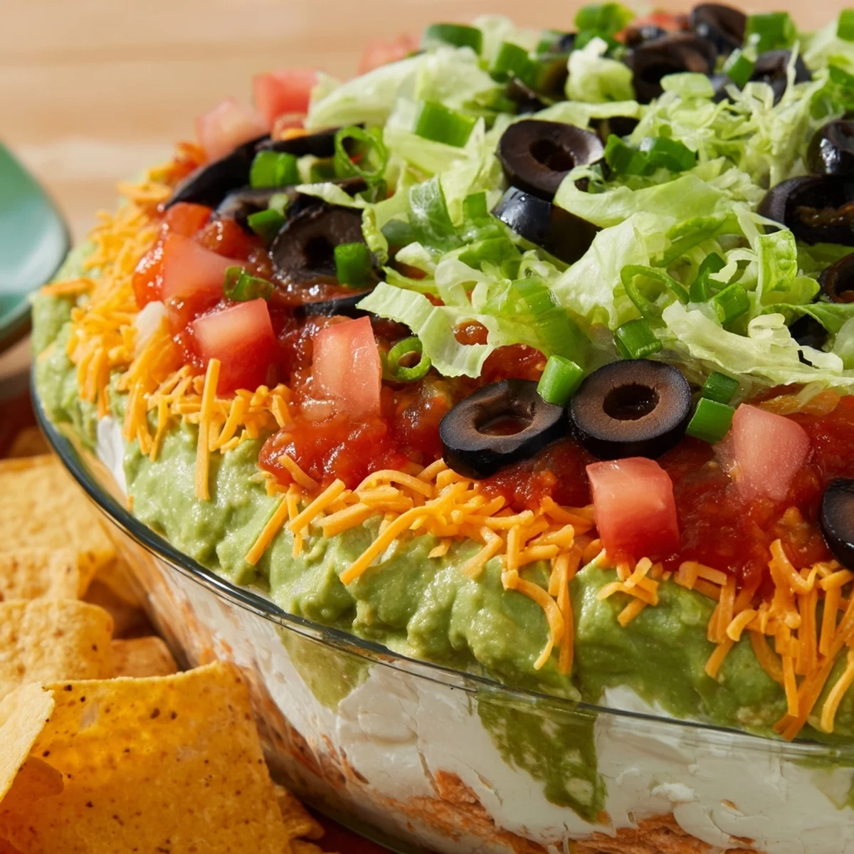 A close-up of End Zone Seven Layer Taco Dip with bright layers of beans, guacamole, cheddar, and fresh toppings.