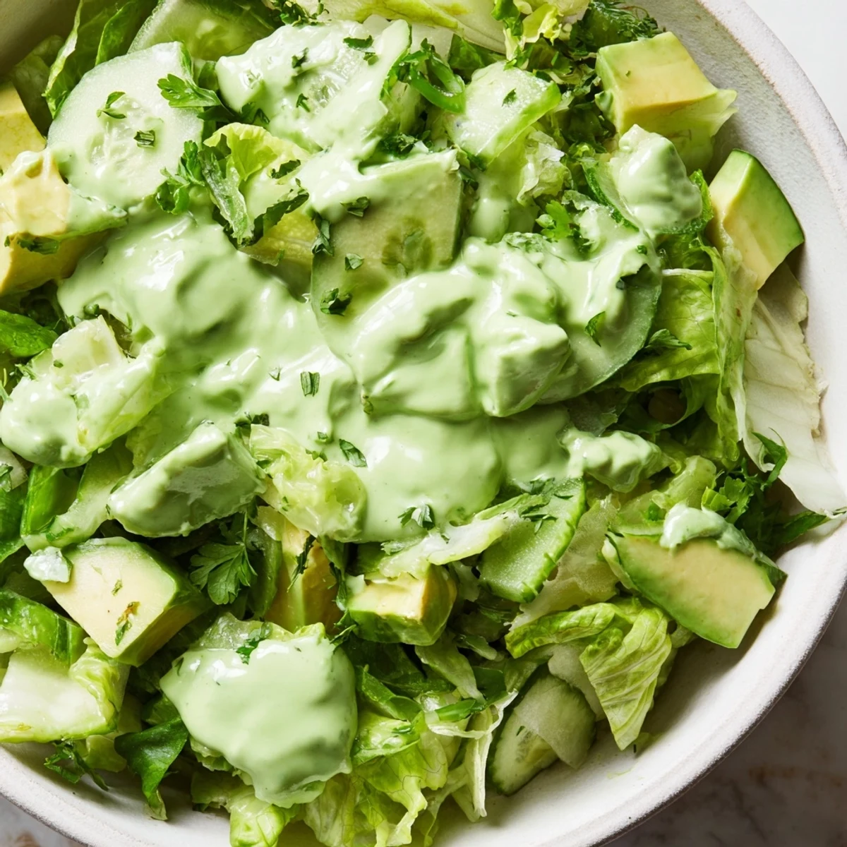 Freshly tossed Green Goddess Salad with crunchy cucumbers and green bell peppers, drizzled generously with herby Green Goddess dressing.