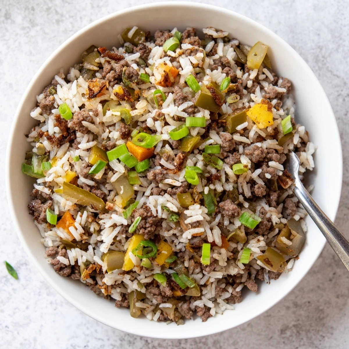 A close-up of vibrant Mardi Gras dirty rice with ground beef, garnished with green onions and parsley on a festive plate.  
