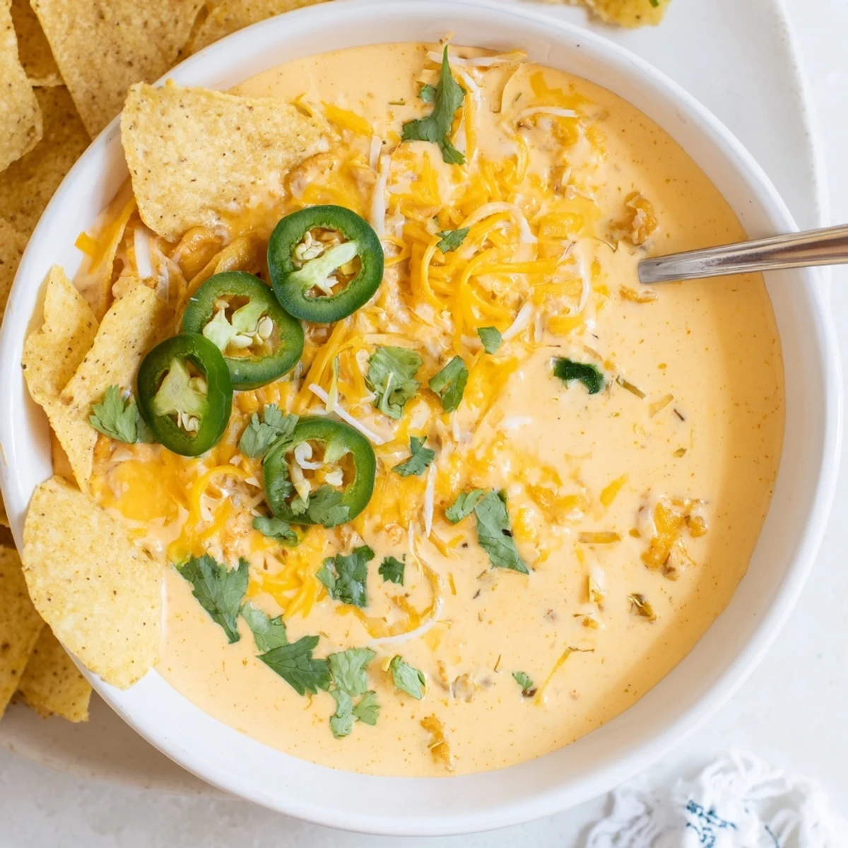 Warm Quarterback Queso Dip with melted cheddar and Monterey Jack, garnished with fresh jalapeño rings and cilantro.