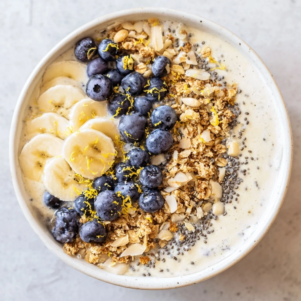 A vibrant, creamy Lemon Blueberry Smoothie Bowl garnished with granola, fresh fruit, and a sprinkle of lemon zest, ready to eat.