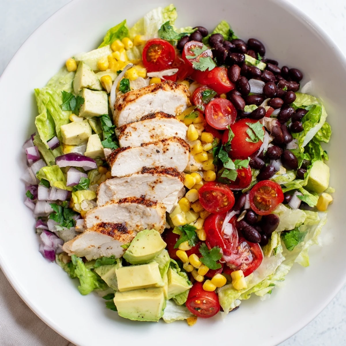 A hearty Southwest Chicken Salad with juicy grilled chicken, black beans, corn, and creamy avocado, dressed in fresh lime.