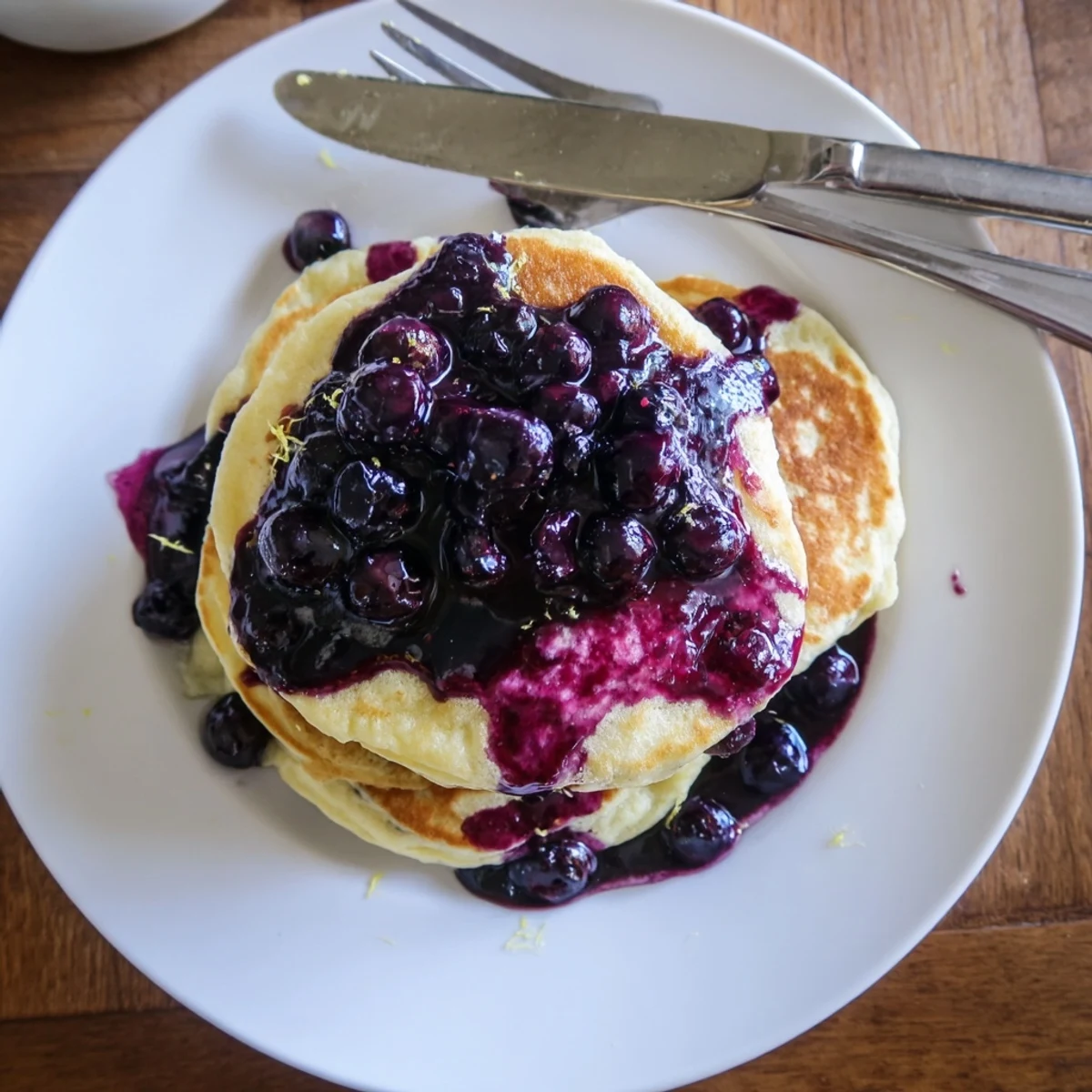 Warm Lemon Ricotta Pancakes with Blueberry Syrup on a plate, ready to be served for a cozy American breakfast.