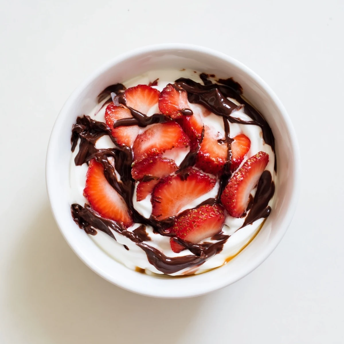 Two servings of Chocolate Covered Strawberry Greek Yogurt topped with sliced strawberries and glossy dark chocolate, ready to enjoy.