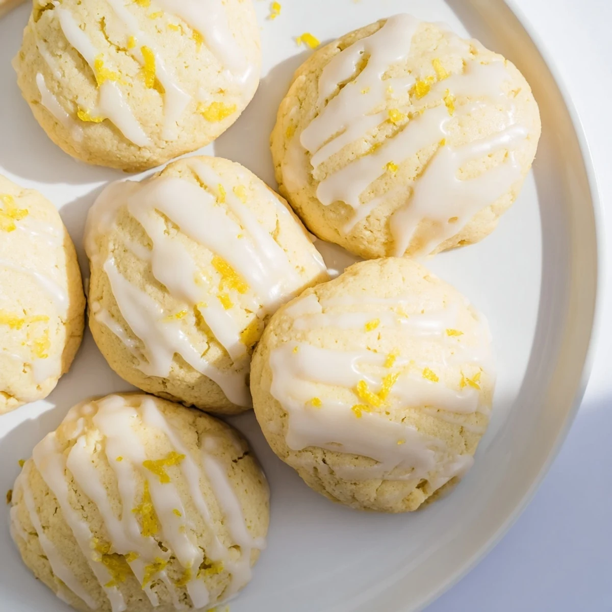 Glazed Lemon Ricotta Cookies on a white marble surface, topped with bright lemon icing and fresh zest for a sweet-tart finish.