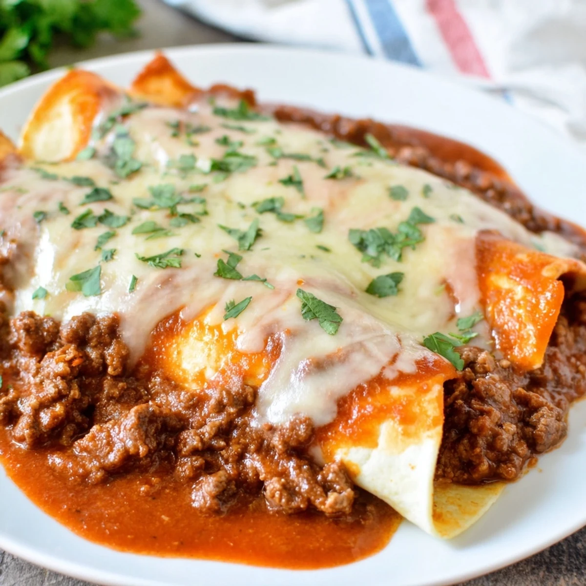Golden-brown Beef Enchiladas with Homemade Red Sauce, bubbling with melted cheese and garnished with fresh cilantro.