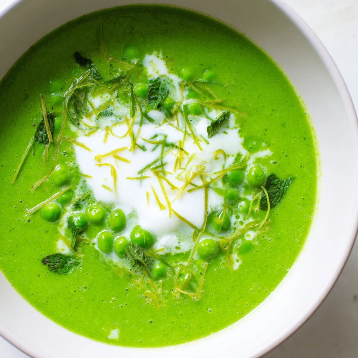 Steaming bowl of Spring Pea Soup with Mint and Crème Fraîche, highlighting its smooth texture and bright green color.