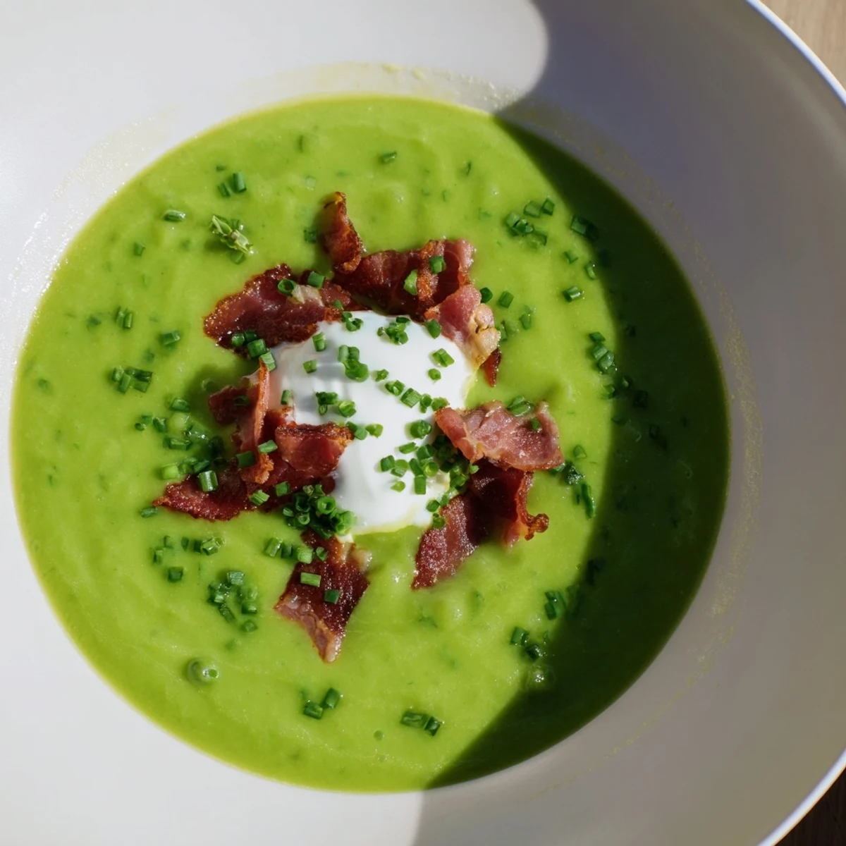 Steaming bowl of Spring Pea Soup featuring bright peas, mint, and golden crispy turkey bacon on top.
