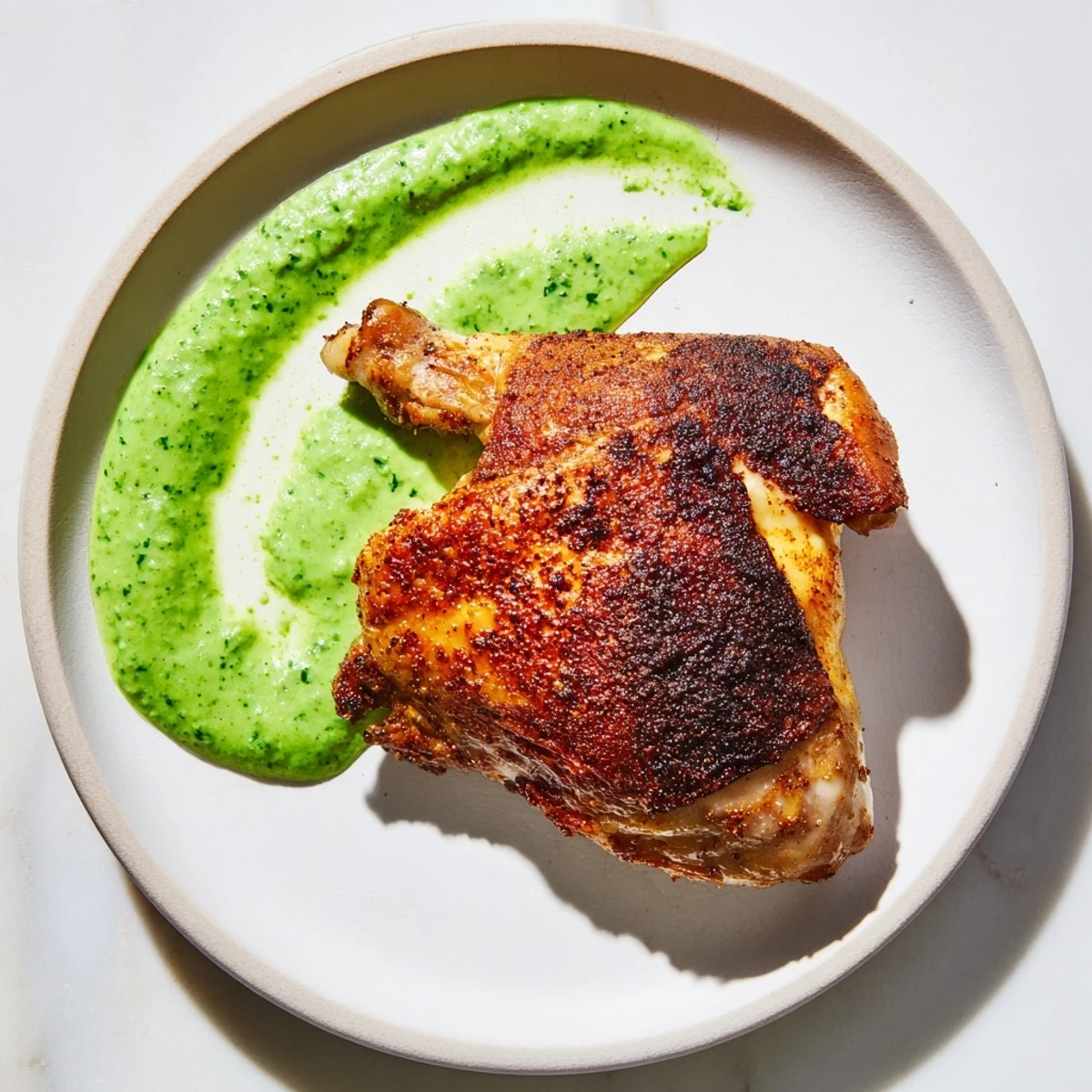 Juicy Peruvian Roast Chicken with Creamy Green Sauce is carved and served alongside roasted potatoes and a vibrant salad.