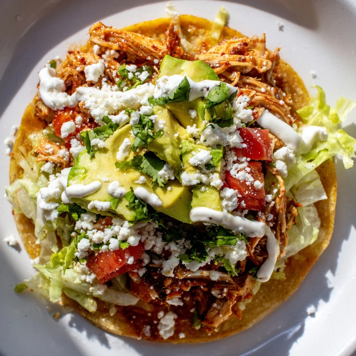 Savory Mini Chicken Tostadas garnished with cilantro and a drizzle of sour cream.
