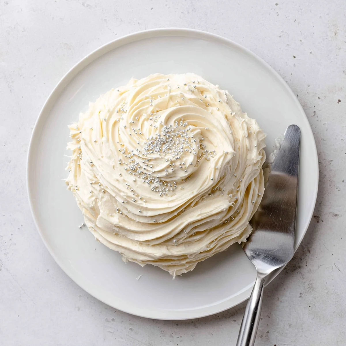 Fluffy white Easy Sugar Cookie Frosting on iced sugar cookies, ready to serve on a bakery rack.