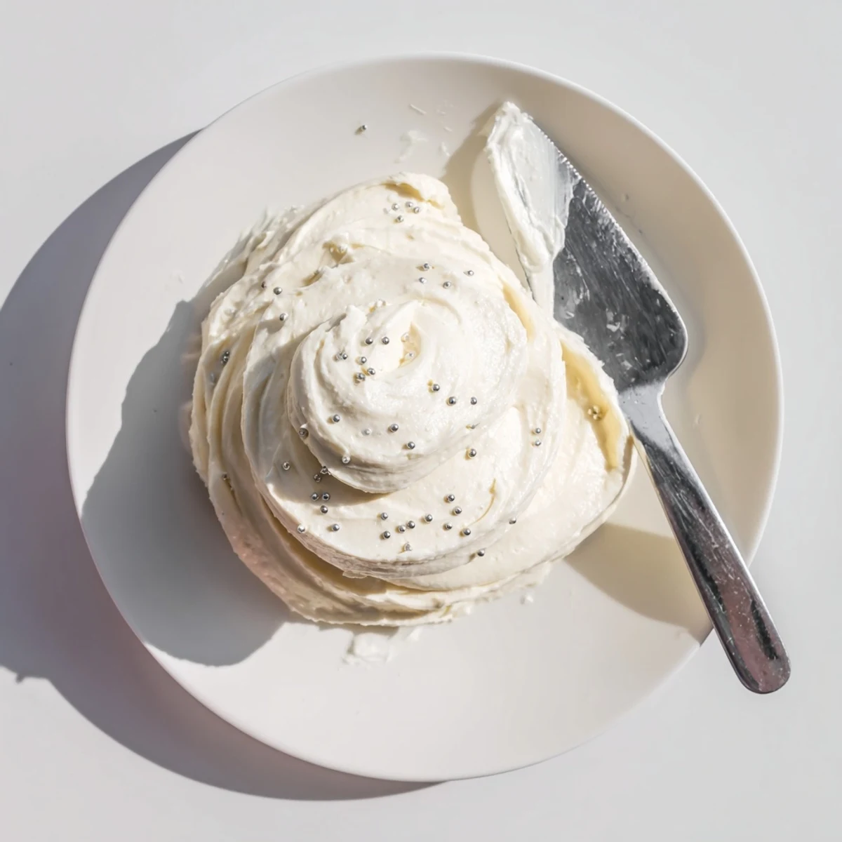 Vanilla Easy Sugar Cookie Frosting frosts colorful sugar cookies on a white platter, perfect for gatherings.
