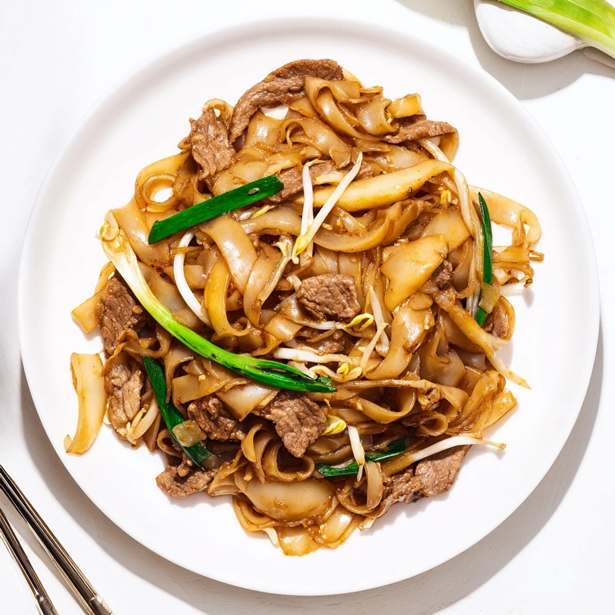 Beef Chow Fun served in a wok, highlighting tender beef strips and crisp vegetables mixed with rice noodles.