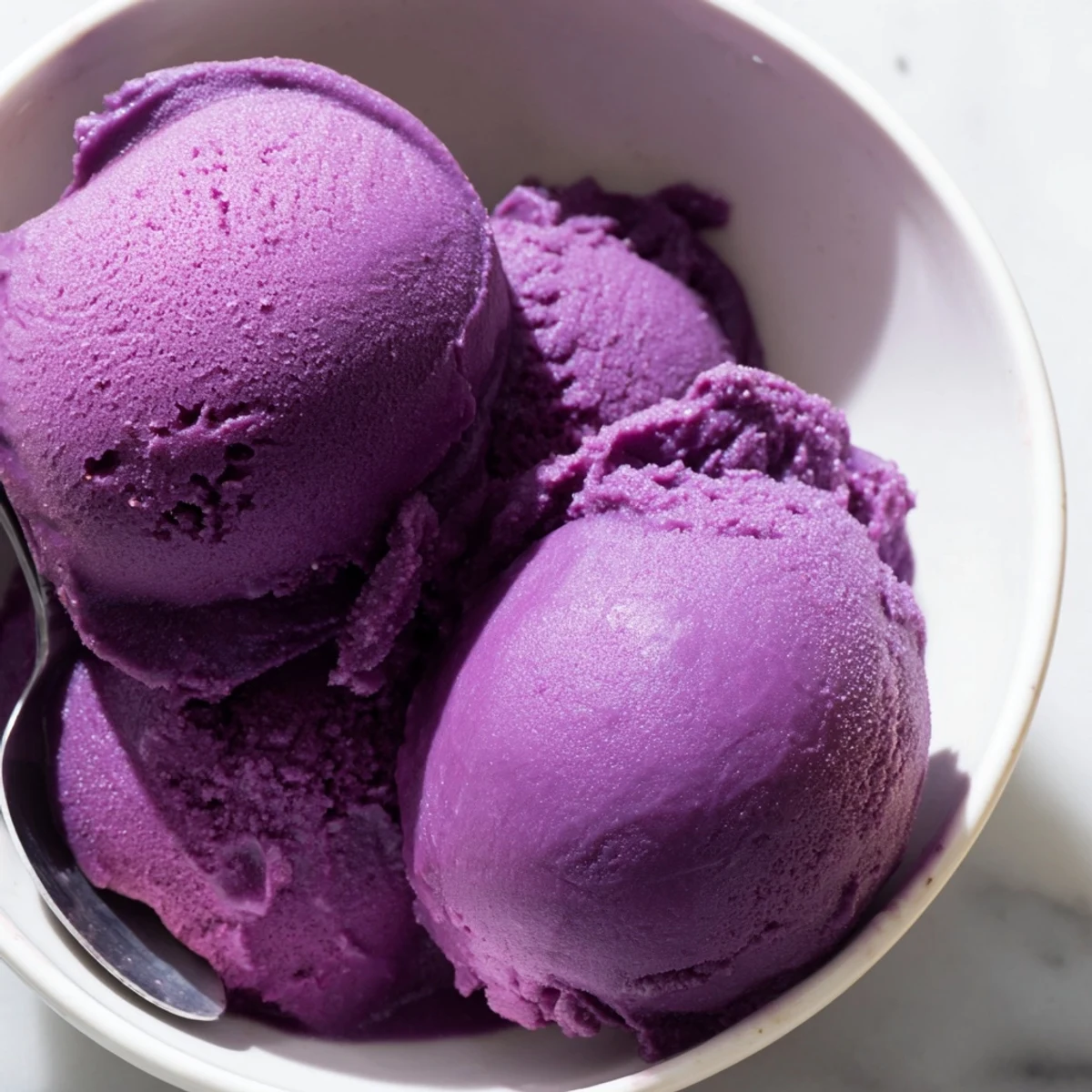 This creamy purple Ube Ice Cream is garnished with toasted coconut flakes on a rustic table.