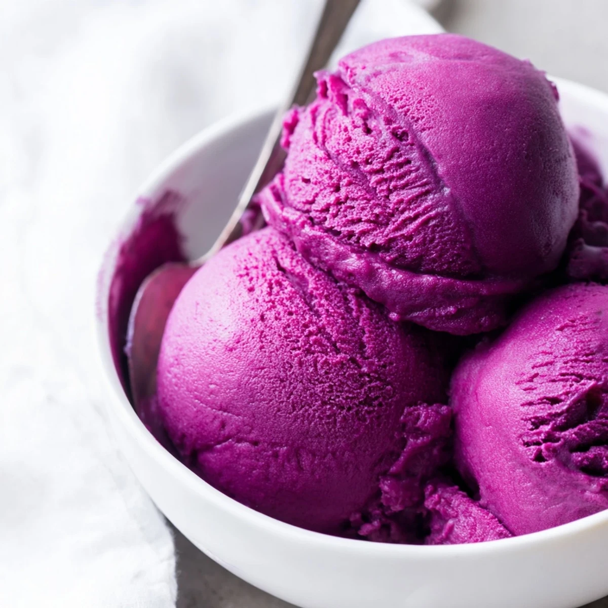 Ube Ice Cream with a rich lavender hue rests in a chilled glass dish ready to serve.