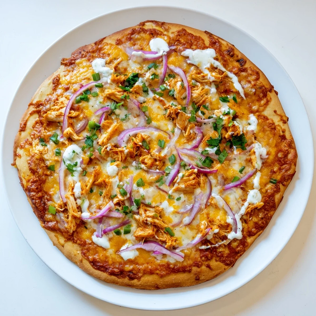 Rustic pizza features shredded chicken tossed in spicy buffalo sauce atop a crisp, golden-brown crust.