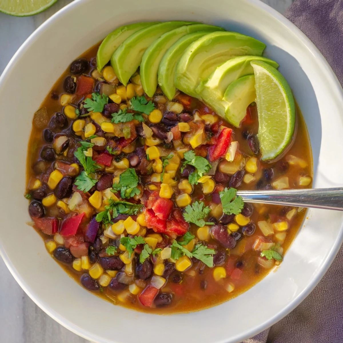 Close-up of Black Bean Corn Chili Lime Delight in a rustic pot with lime wedges on the side.