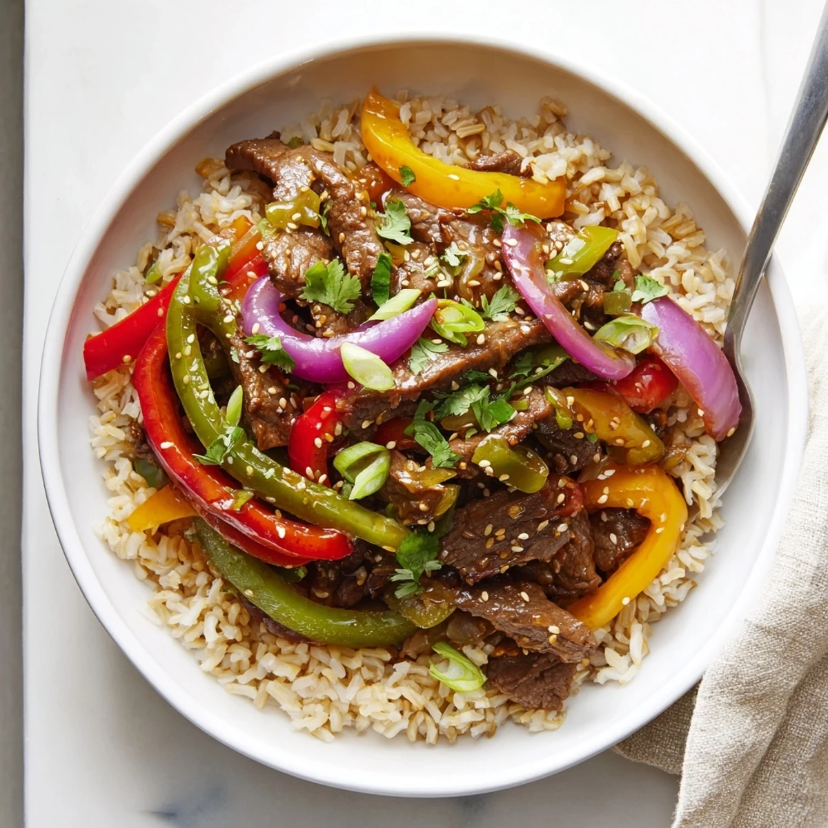 Healthy Beef and Pepper Rice Bowl shows glossy garlic ginger sauce coating beef and peppers over rice.