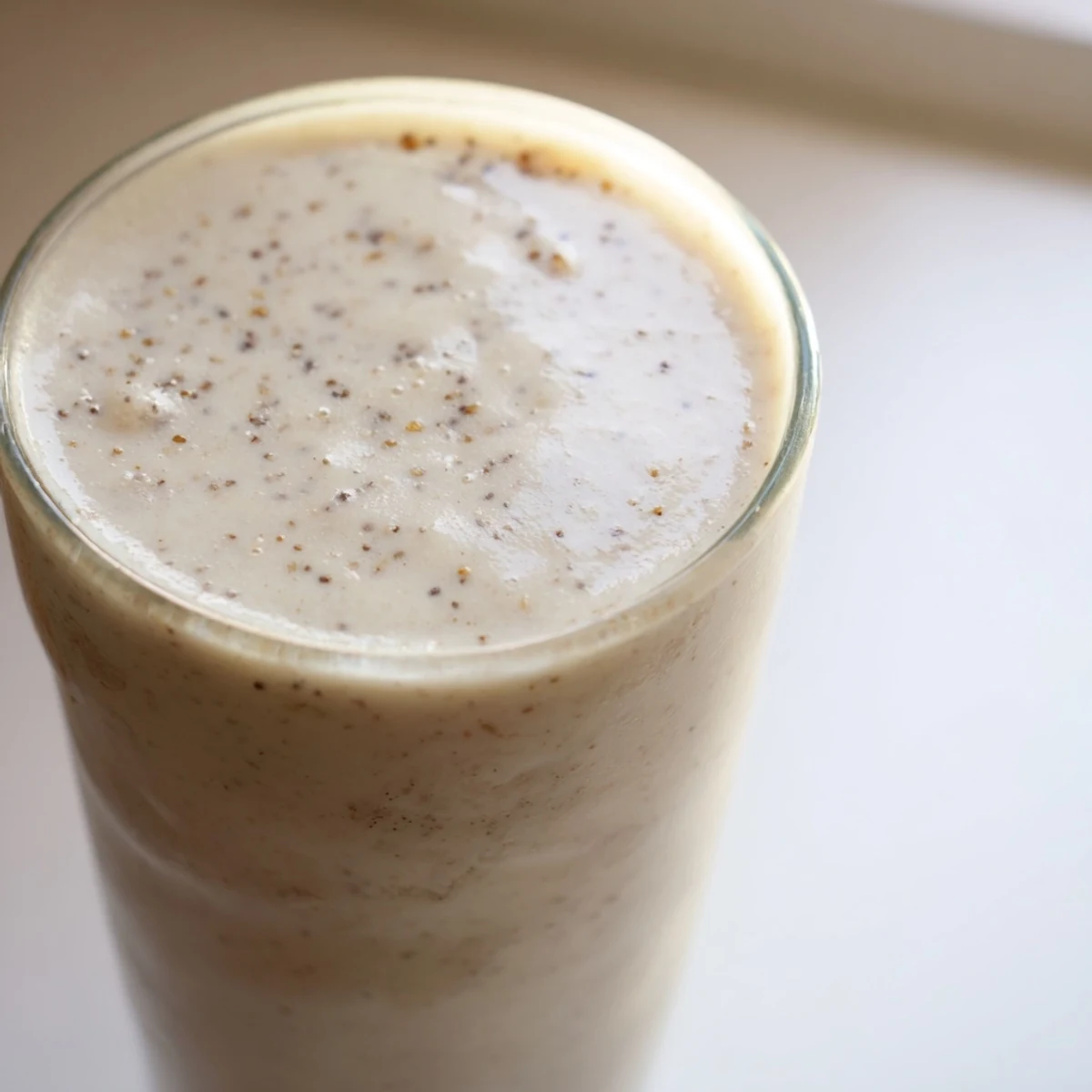 Creamy Greek yogurt banana smoothie poured into tall glasses topped with fresh banana slices