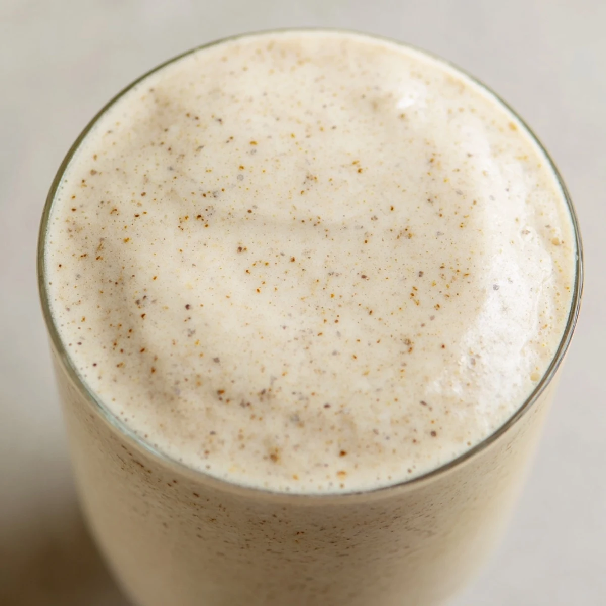 Golden yellow Greek yogurt banana smoothie in clear glass showing smooth creamy texture