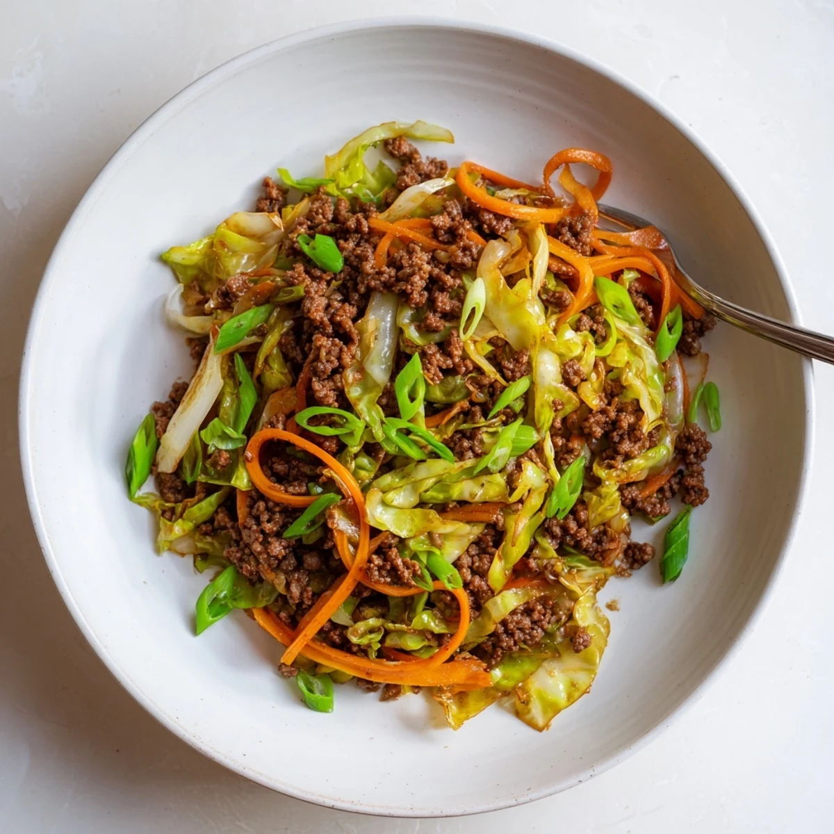 Savory Asian-style ground beef and cabbage stir fry topped with fresh green onion garnish