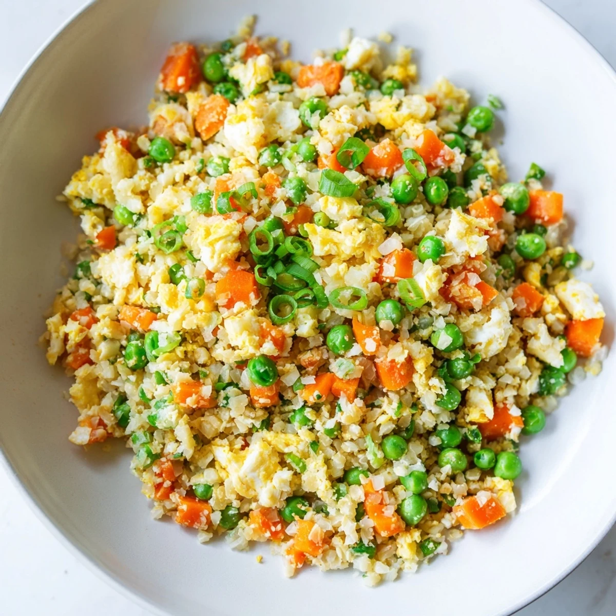 Close-up of low carb cauliflower fried rice being stir-fried with colorful vegetables in a wok