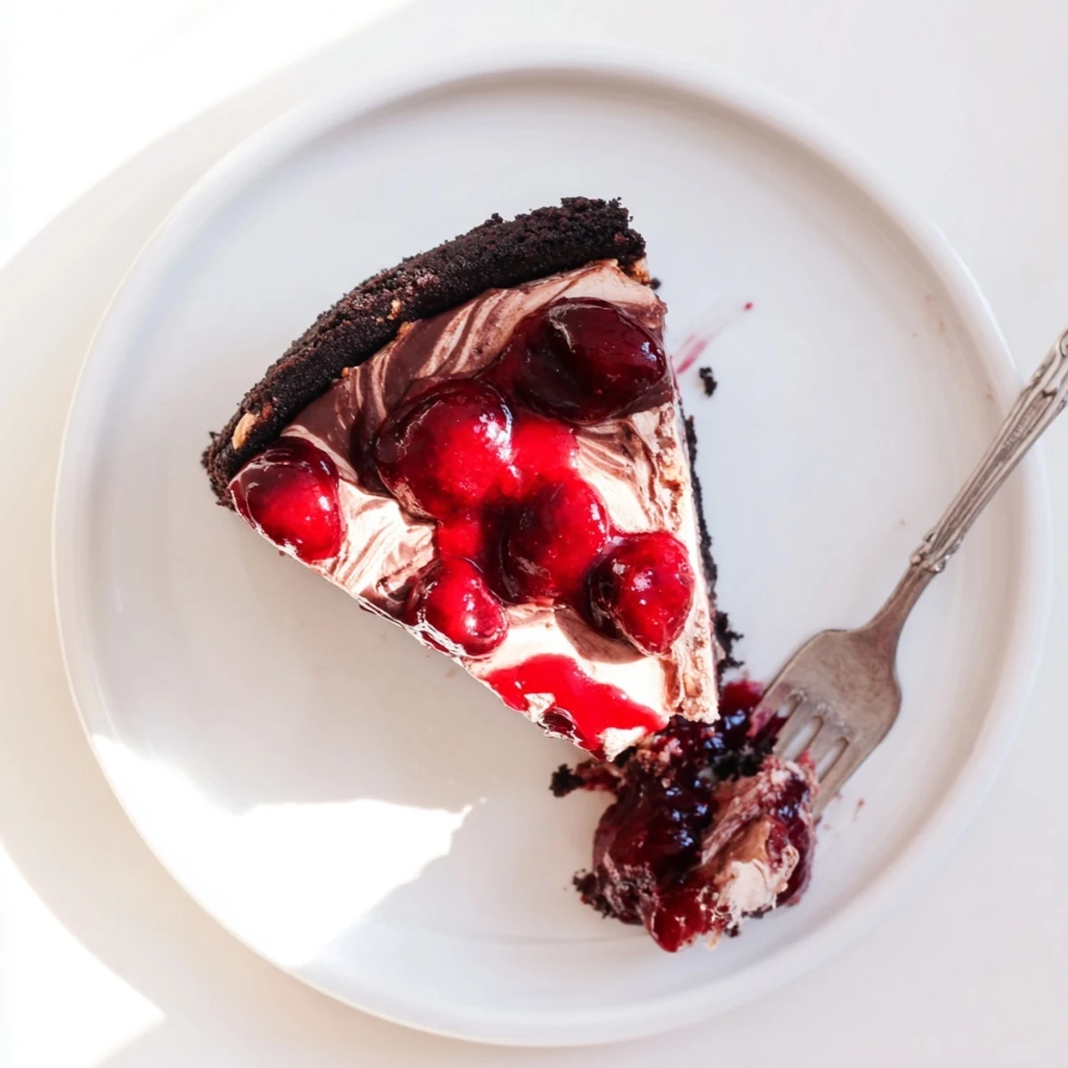 Rich dark chocolate cheesecake with vibrant cherry compote garnished with chocolate shavings