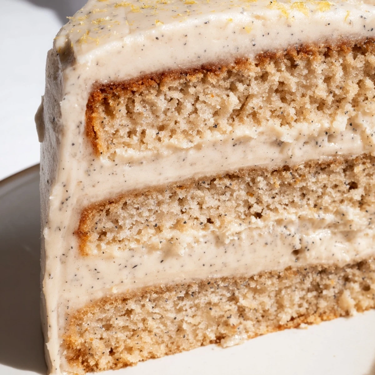 Slice of London Fog cake revealing Earl Grey-infused layers with creamy vanilla bean frosting and garnish of lemon zest