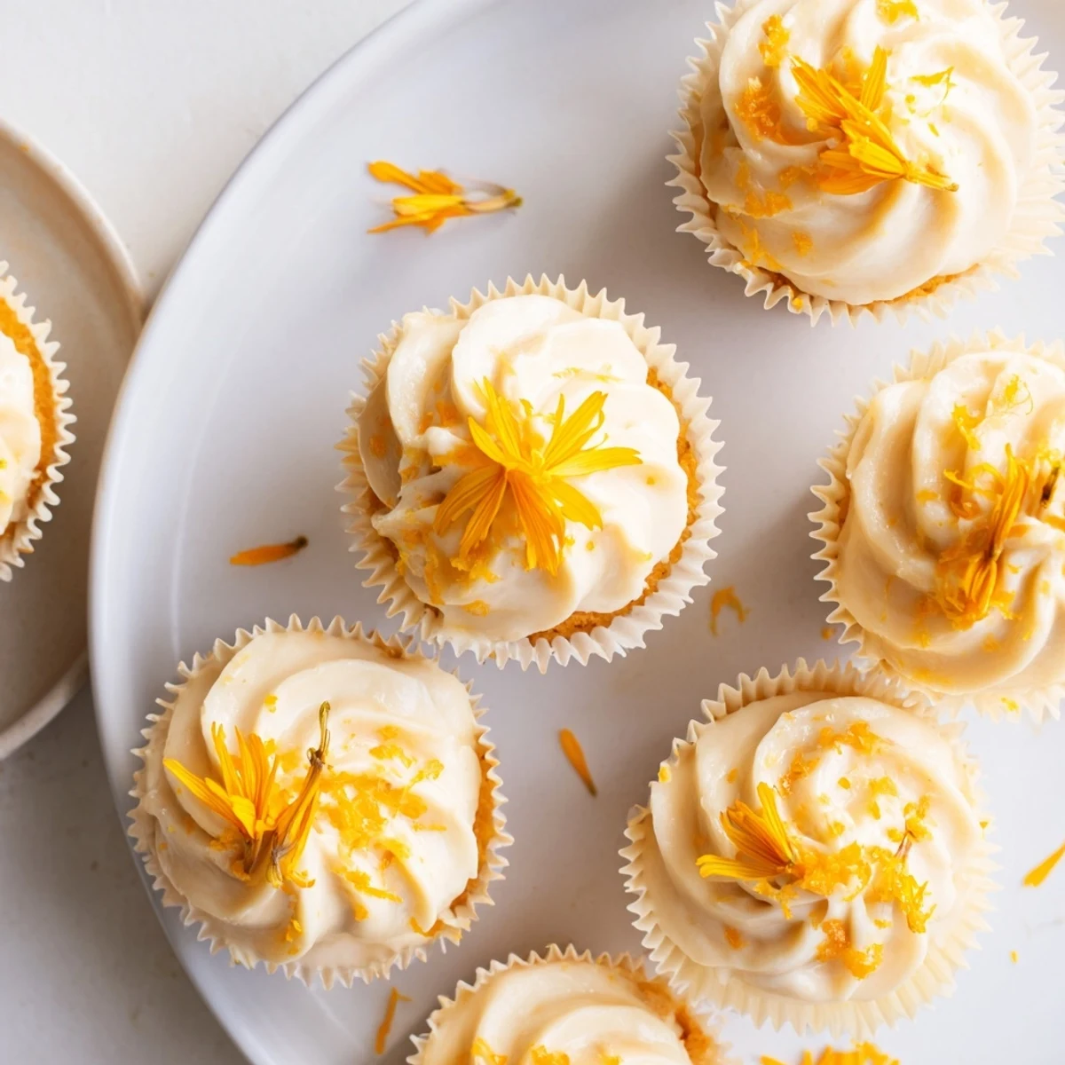 Delicate floral cupcakes with light orange blossom buttercream frosting on a white serving plate