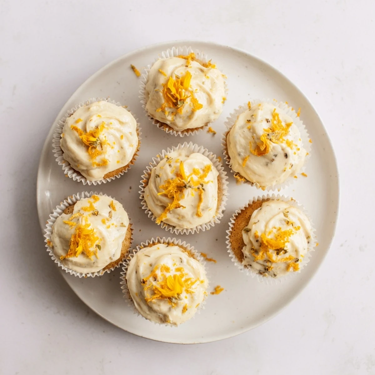 Fluffy orange blossom cupcakes topped with creamy citrus frosting and fresh orange zest garnish