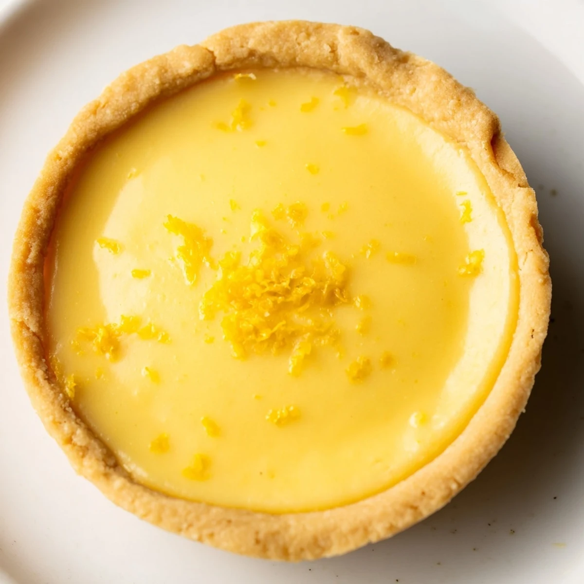 Bite-sized vegan lemon tarts topped with fresh zest and berries arranged on a rustic wooden board for serving