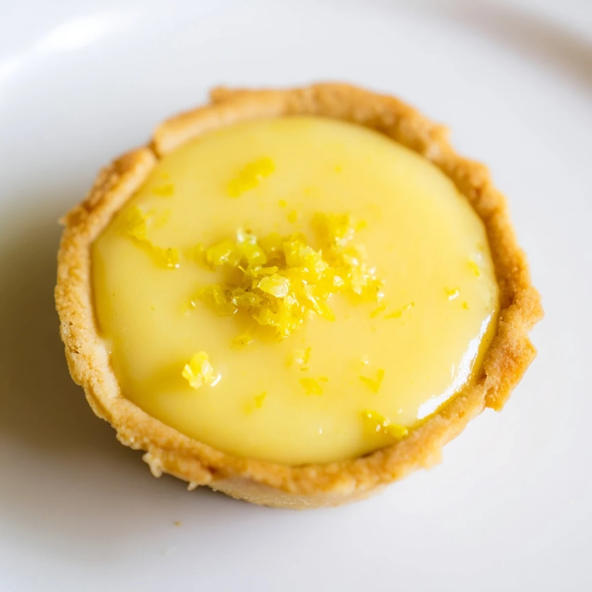 Creamy yellow vegan lemon filling nestled in golden baked tart shells garnished with powdered sugar on a dessert platter