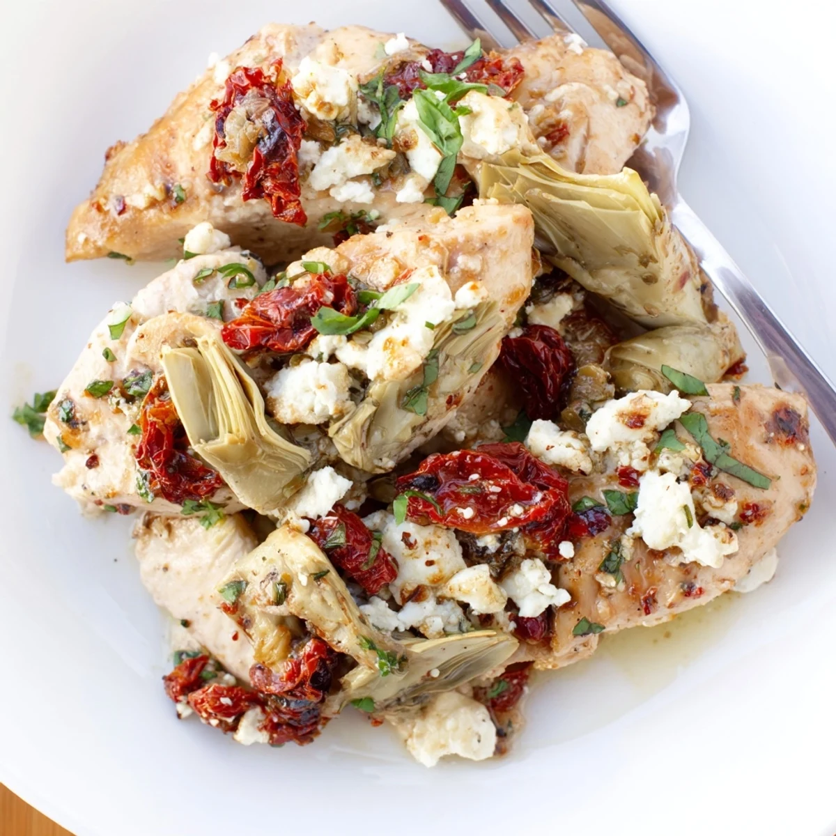 Golden broiled artichoke chicken topped with melted feta cheese and fresh herbs