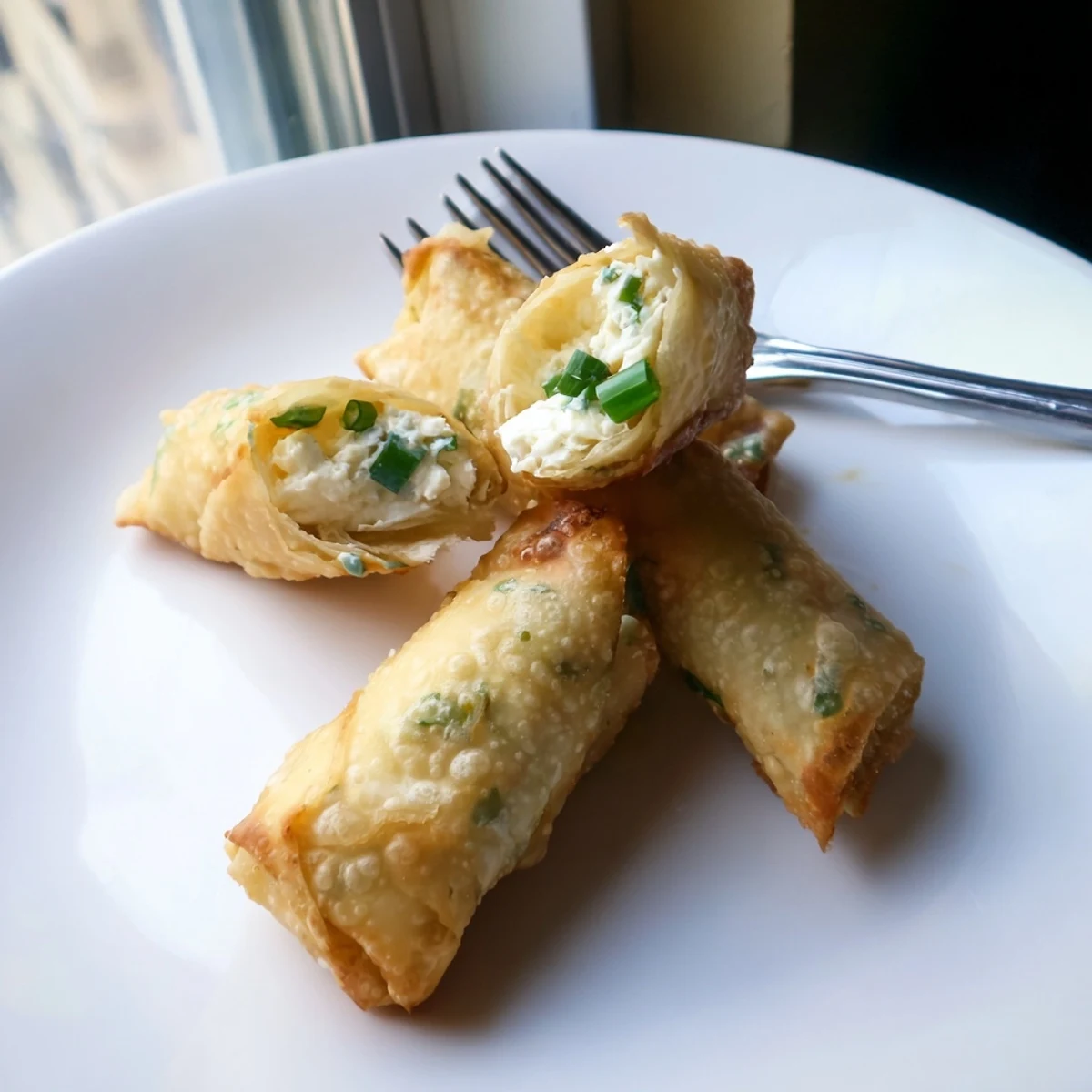 Crispy appetizer featuring savory crab and cream cheese wrapped in golden brown fried egg roll pastry