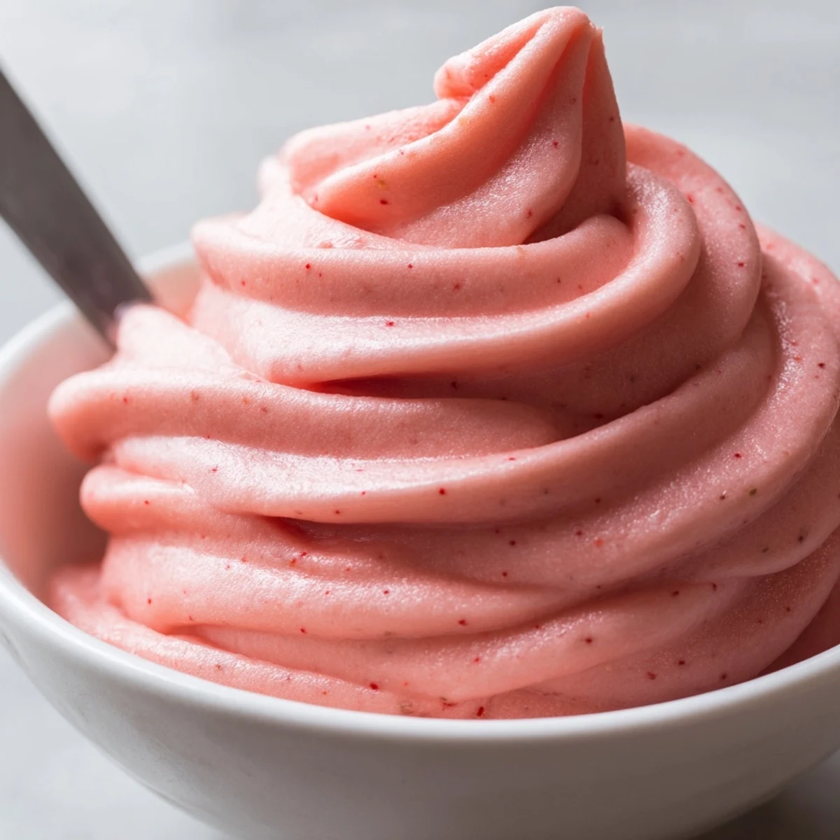 Vibrant pink frozen strawberry Dole whip delight scooped into a waffle cone with coconut flakes
