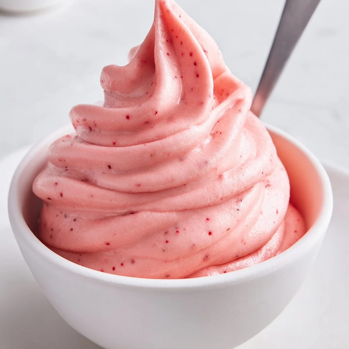 Creamy frozen strawberry Dole whip delight swirled into a bowl topped with fresh strawberries
