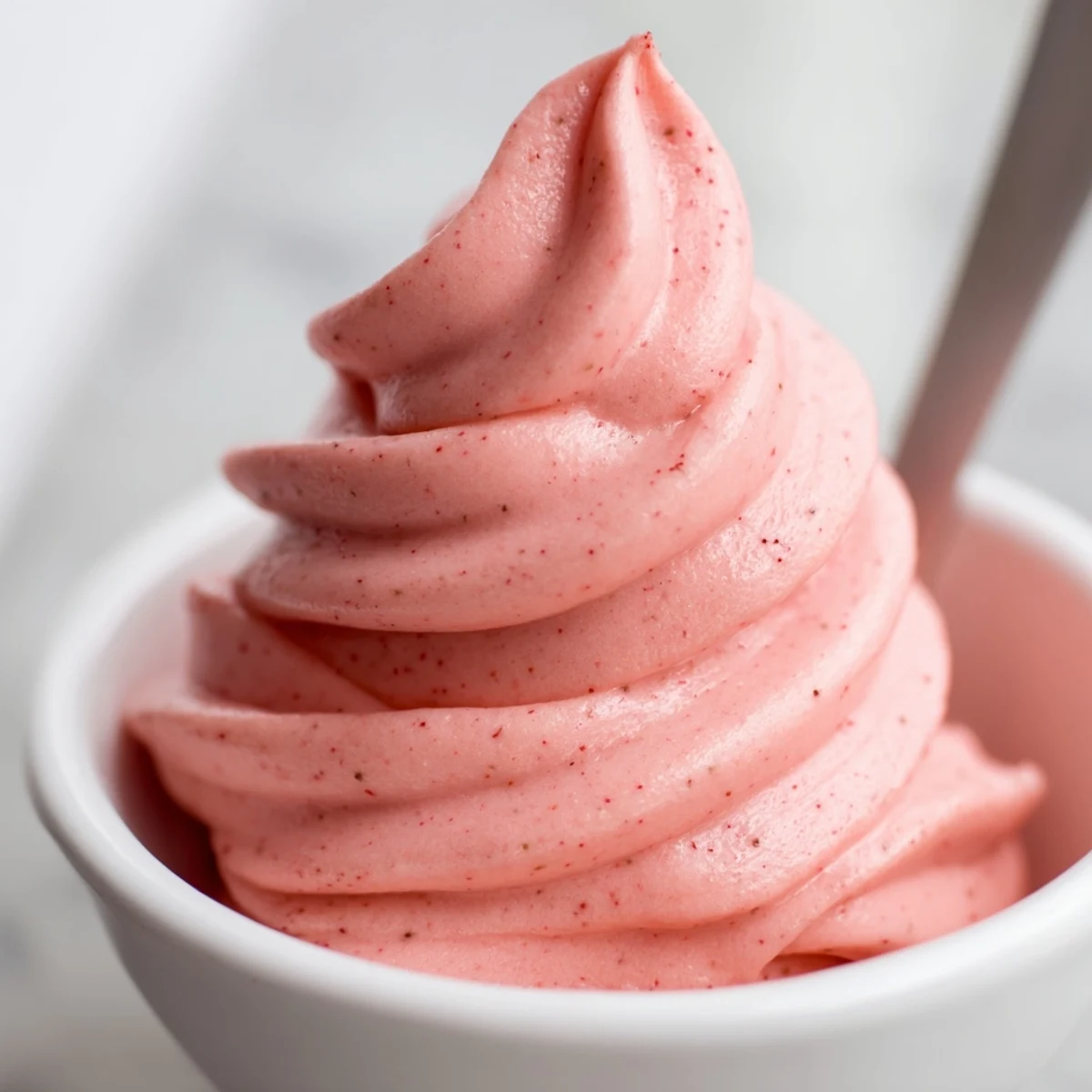 Smooth dairy-free frozen strawberry Dole whip delight served in a glass with a striped straw