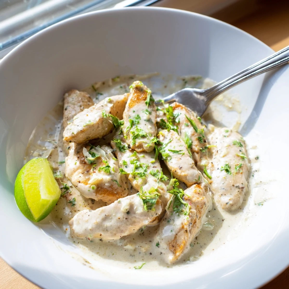 Tender chicken breasts coated in rich coconut lime sauce, topped with chopped fresh cilantro and served with zesty lime slices.