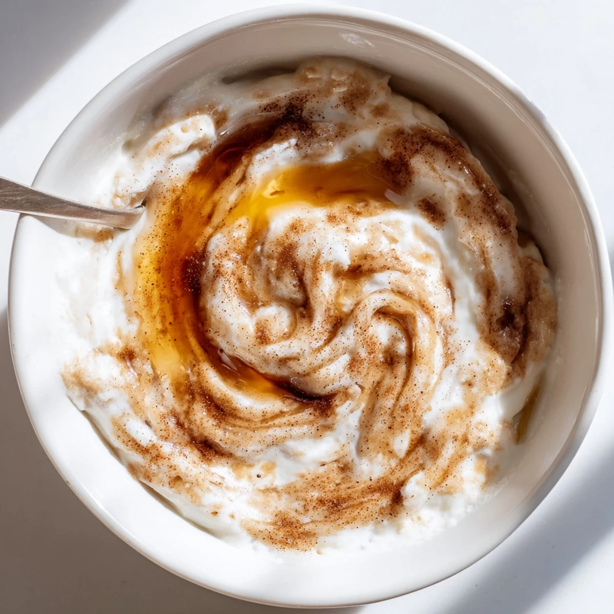 Creamy Greek yogurt cinnamon roll dip swirled with cinnamon and served with fresh sliced apples and strawberries on a white platter