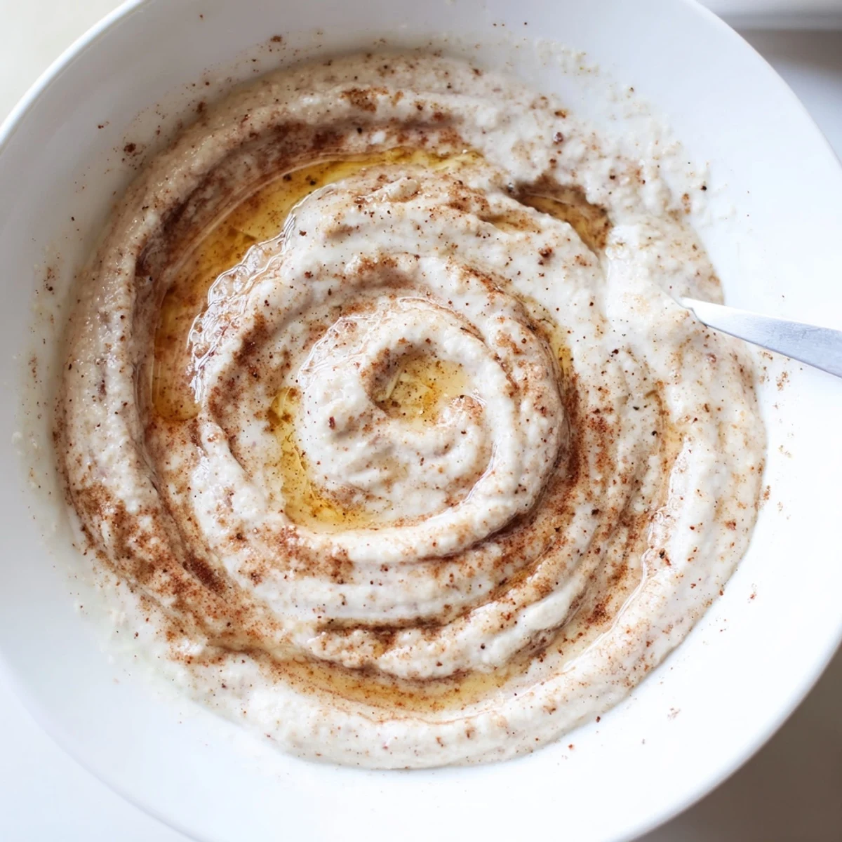 Protein-packed cinnamon roll dip featuring Greek yogurt with marbled cinnamon swirl topping surrounded by colorful fresh fruit dippers