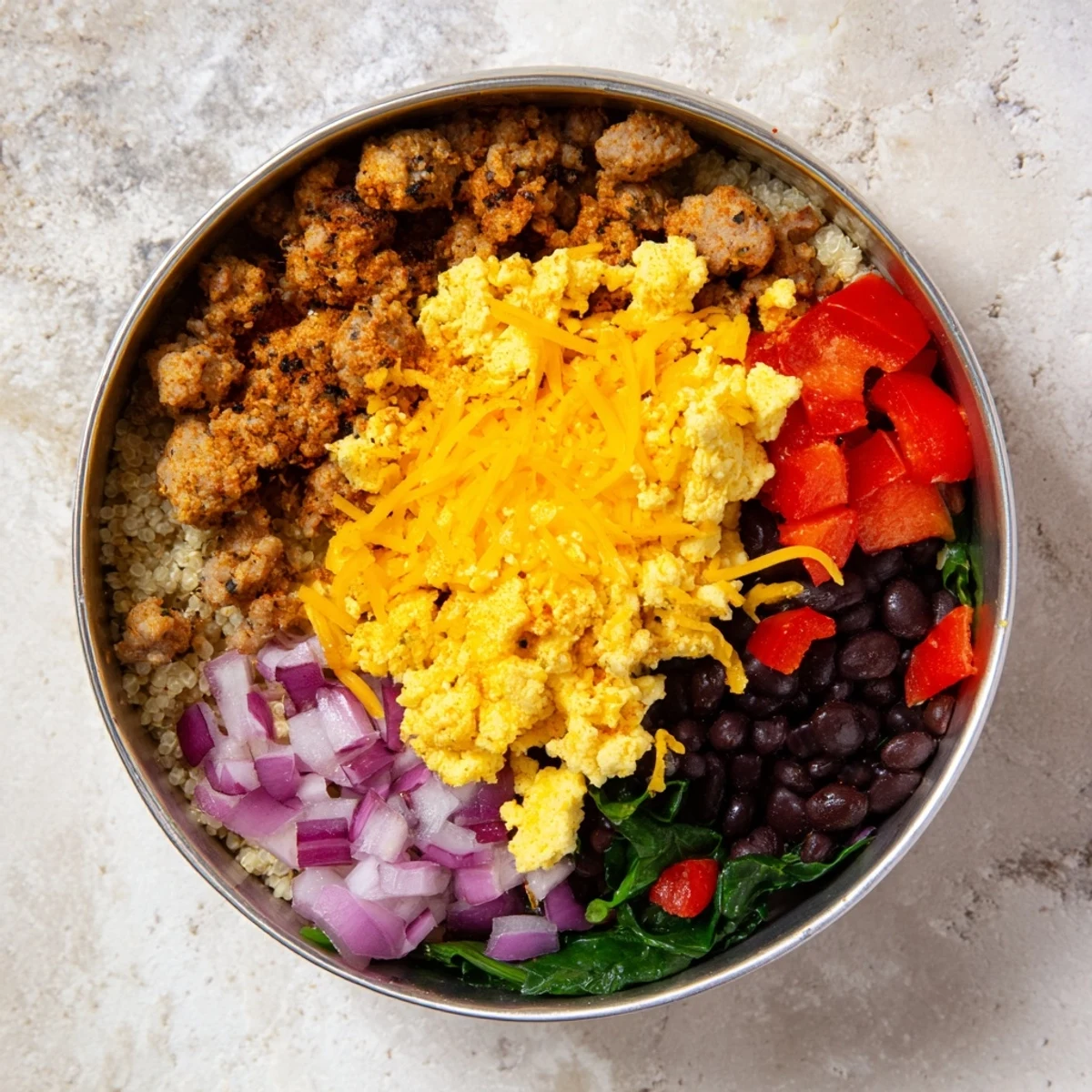 Hearty breakfast bowl featuring fluffy eggs, turkey sausage, black beans, and bell pepper over a bed of wholesome cooked quinoa